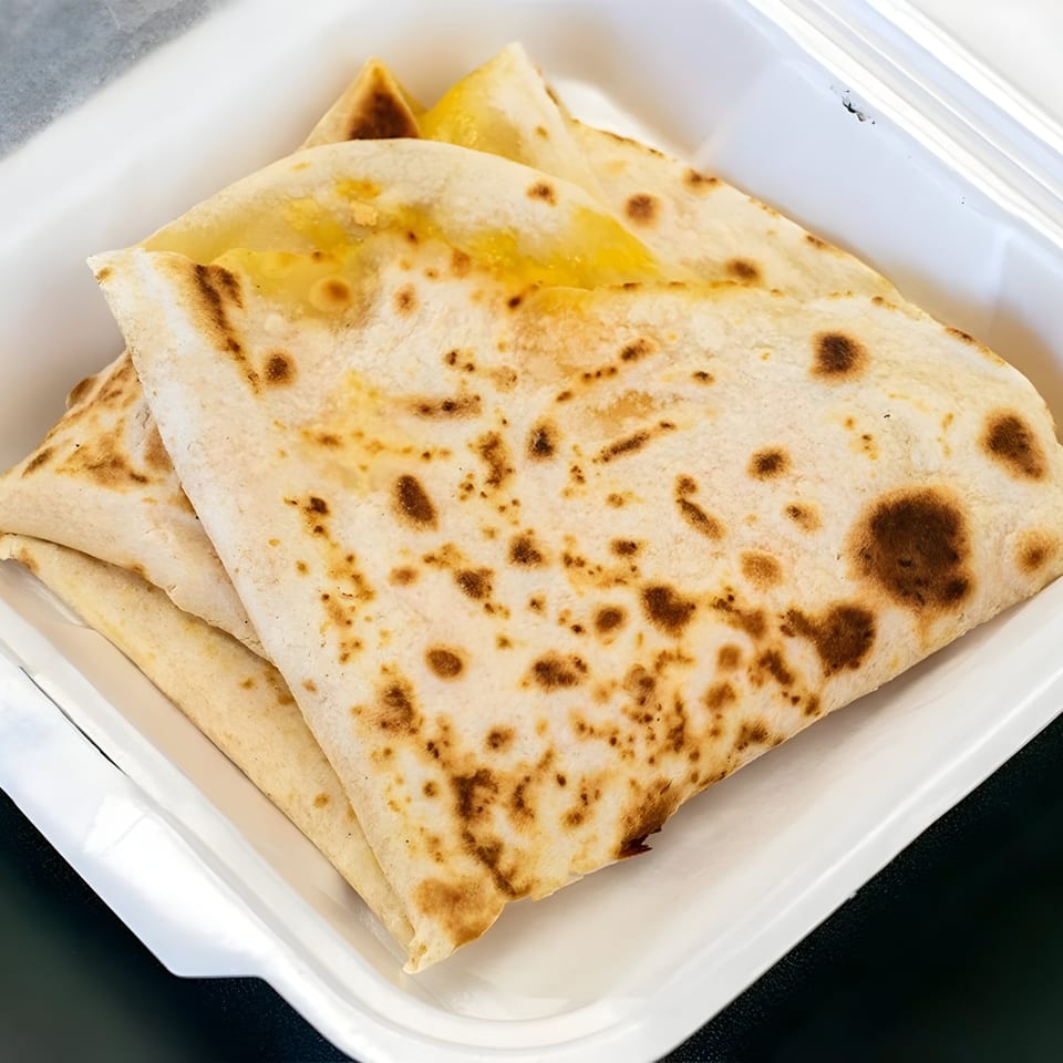 Warm, folded cheese quesadillas with browned tortillas, served in a white to-go container.